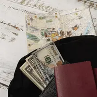 Dompet, paspor, sejumlah uang, dan peta dunia di atas sebuah meja (Foto Dok: Freepik/freepik).