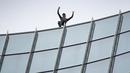 Pendaki kota Prancis, Alain Robert, yang dikenal sebagai "French Spiderman", mengangkat tangannya setelah memanjat gedung Skyper setinggi 153,8 m di Frankfurt am Main, Sabtu (28/9/2019). (AFP Photo/Daniel Roland)