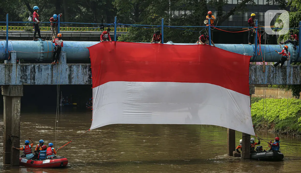 Sejumlah relawan membentangkan bendera Merah Putih di aliran kali
Ciliwung di kawasan Sudirman, Jakarta, Minggu (22/8/2021). Pembentangan atau pengibaran bendera Merah Putih tersebut dilaksanakan untuk memperingati HUT ke-76 RI. (Liputan6.com/Faizal Fanani)
