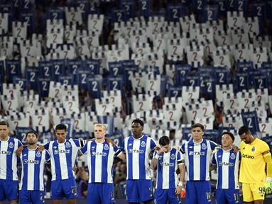 Sejumlah pemain FC Porto mengheningkan cipta dengan latar belakang para penonton yang sedang memegang plakat bergambar nomor punggung dua untuk mengenang kepergian Diogo Costa sebelum laga Liga Portugal 2025/2026 melawan Vitoria Guimaraes SC di Estadio Do Dragao, Porto, Portugal, Senin (11/08/2025) waktu setempat. (AFP/Miguel Riopa)