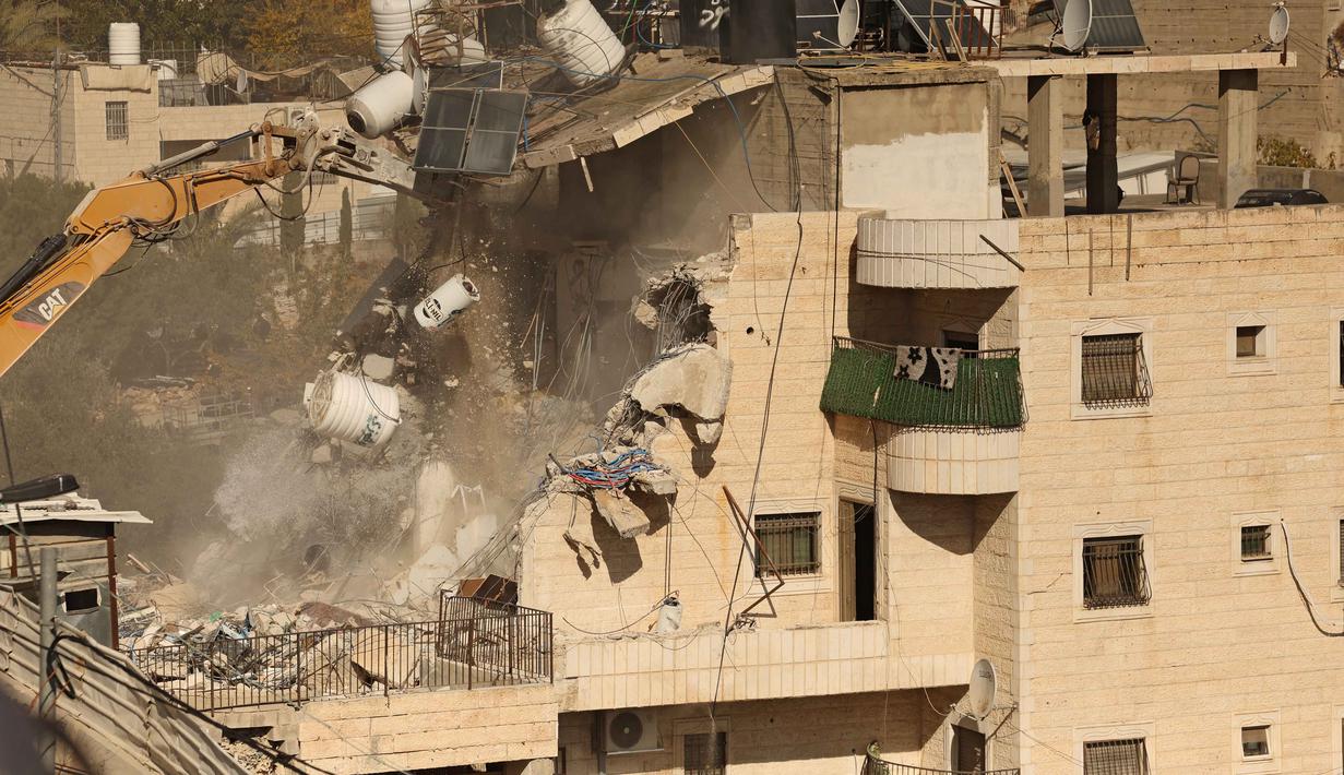 Mereka juga mengkritik langkah Israel ini sebagai upaya Tel Aviv untuk memajukan kepentingan permukiman Yahudi mereka. Tampak dalam foto, sebuah ekskavator merobohkan sebuah bangunan yang dibangun tanpa izin di daerah Wadi Qaddum dekat lingkungan Silwan di Yerusalem timur pada Senin 22 Desember 2025. (Ahmad GHARABLI/AFP)