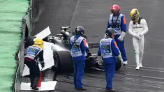 Pembalap Mercedes, Lewis Hamilton (kanan) melihat mobilnya usai menabrak saat kualifikasi F1 GP Brasil di sirkuit Interlagos di Sao Paulo, Brasil (11/11). Mobil Hamilton itu hancur sehingga bendera merah harus berkibar. (AFP Photo/Nelson Almeida)