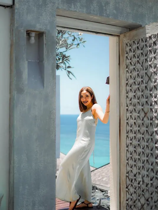 Gisella Anastasia tampil simple dengan satin dress warna biru. Warna dress yang dikenakannya nampak menyatu dengan latar air laut [@gisel_la]