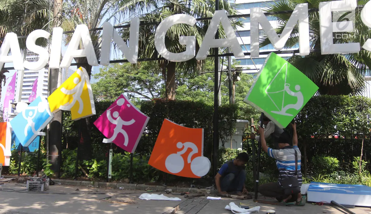Pekerja memasang neon box Asian Games di depan Balai Kota DKI Jakarta, Jumat (6/7).Lampu neon box berwarna warni yang dipasang menggambarkan berbagai cabang olahraga yang akan dipertandingkan dalam Asian Games 2018. (Liputan6.com/Arya Manggala)