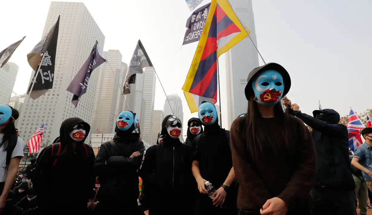 Demonstran mengenakan topeng saat berkumpul untuk menunjukkan dukungan kepada Uighur dan perjuangan mereka terhadap hak azasi manusia (HAM) di Hong Kong, Minggu (22/12/2019). Demonstran memprotes kebijakan China terkait minoritas Uighur. (AP Photo/Lee Jin-man)
