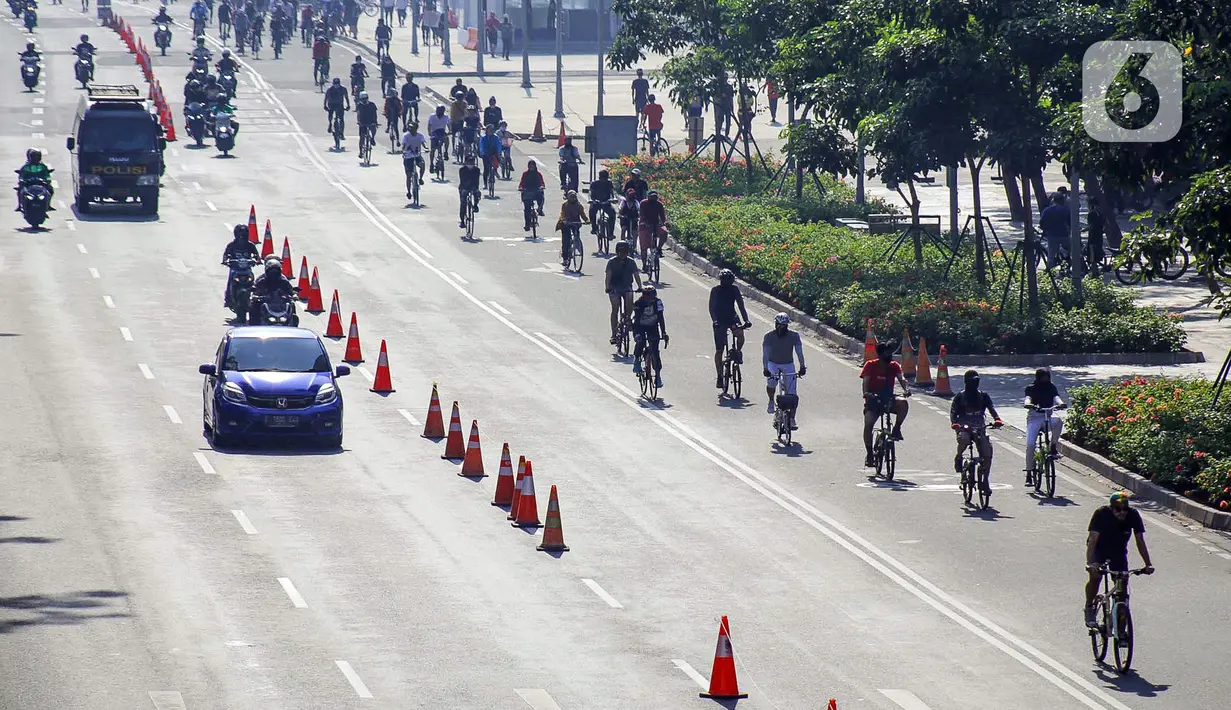 Warga berolahraga menggunakan sepeda di sepanjang Jalan Sudirman, Jakarta, Minggu (26/7/2020). Pemprov DKI Jakarta akan memperluas jalur sepeda sementara yang disiapkan sepanjang Jalan Medan Merdeka Barat hingga Jalan Sudirman dengan memakai 2-3 lajur di sebelah kiri. (Liputan6.com/Faizal Fanani)