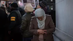 Afaf Nasher telihat khusyuk saat menjalankan salat dikerumunan pendemo lainnya sebelum melakukan aksi protes terhadap Presiden AS Donald Trump di Washington Square Park di New York, AS (25/1). (AFP/Bryan R. Smith)