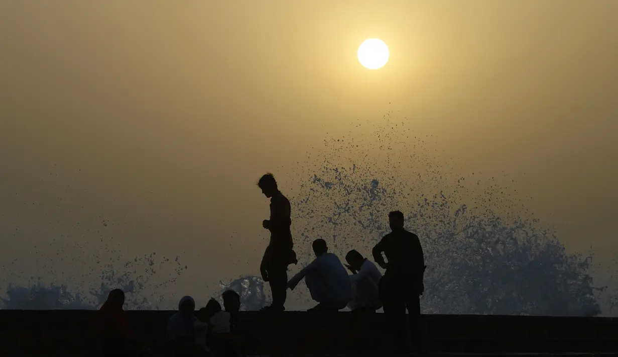 Para pemuda menikmati percikan air ombak selama musim panas di laut Arab di Karachi, Pakistan (14/6/2019). Memasuki musim panas, warga Pakistan ramai-ramai mendinginkan tubuhnya di laut. (AFP Photo/Asif Hassan)