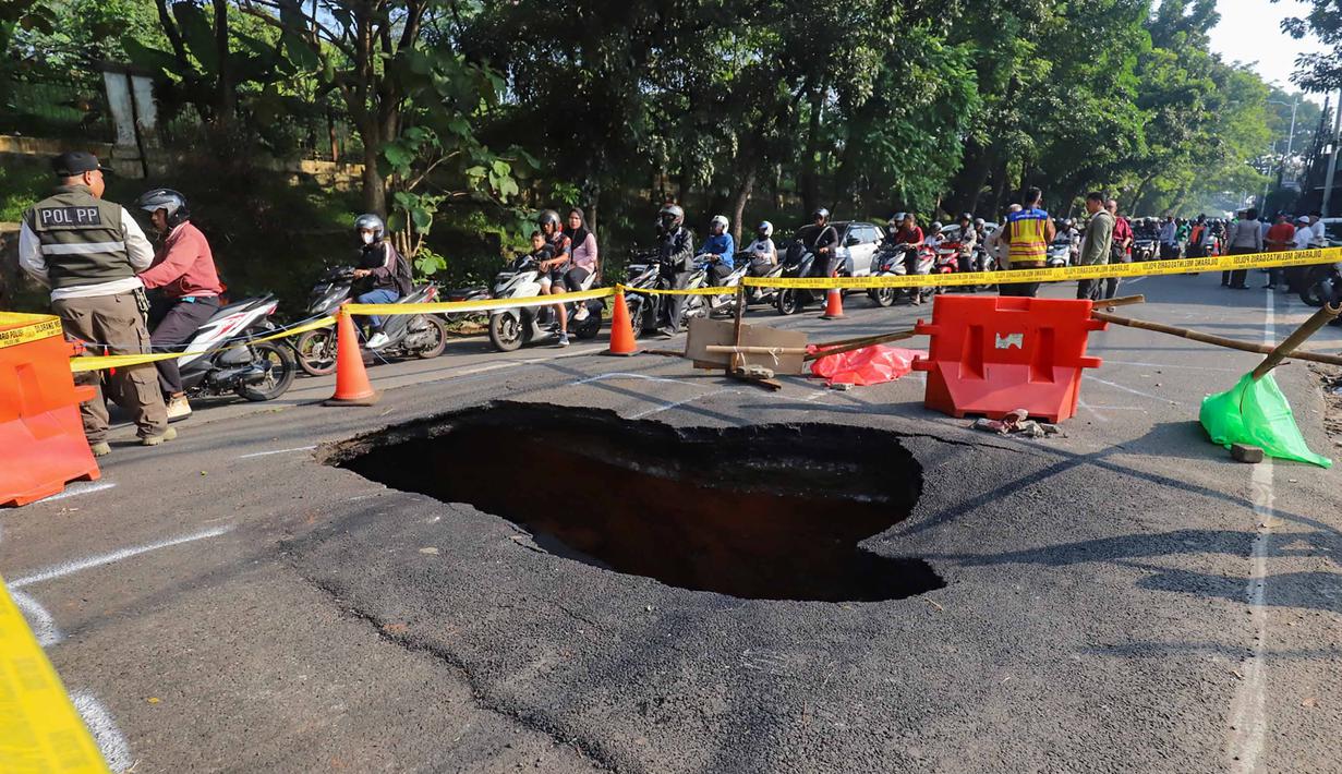 Pengendara melintas di sisi ruas jalan yang ditutup sebagian akibat amblas di Jalan Raya Lenteng Agung, Jakarta Selatan, Jumat (29/5/2026). (merdeka.com/Arie Basuki)