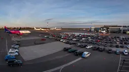 Orang-orang duduk di mobil mereka saat menonton film di bioskop drive-in di area apron bandara kota Vilnius, Lithuania pada 29 April 2020. Bandara tersebut kini sepi penumpang, akibat pembatasan perjalanan internasional untuk mengatasi penyebaran virus corona covid-19. (AP/Mindaugas Kulbis)