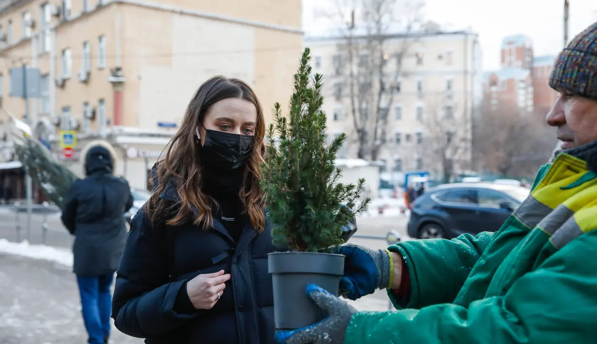 Seorang wanita membeli pohon untuk perayaan Tahun Baru di sebuah pasar di pusat kota Moskow, Rusia (27/12/2020). Rusia memiliki tradisi tahunan dalam memilih, mendekorasi, dan memajang pohon Tahun Baru publik utama negara itu. (Xinhua/Maxim Chernavsky)