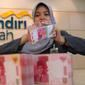 Petugas menghitung uang di Bank Mandiri Syariah, Jakarta, Kamis (14/7). Otoritas Jasa Keuangan (OJK) memastikan hanya bank syariah besar yang dilibatkan dalam pelaksanaan kebijakan pengampunan pajak. (Liputan6.com/Angga Yuniar)