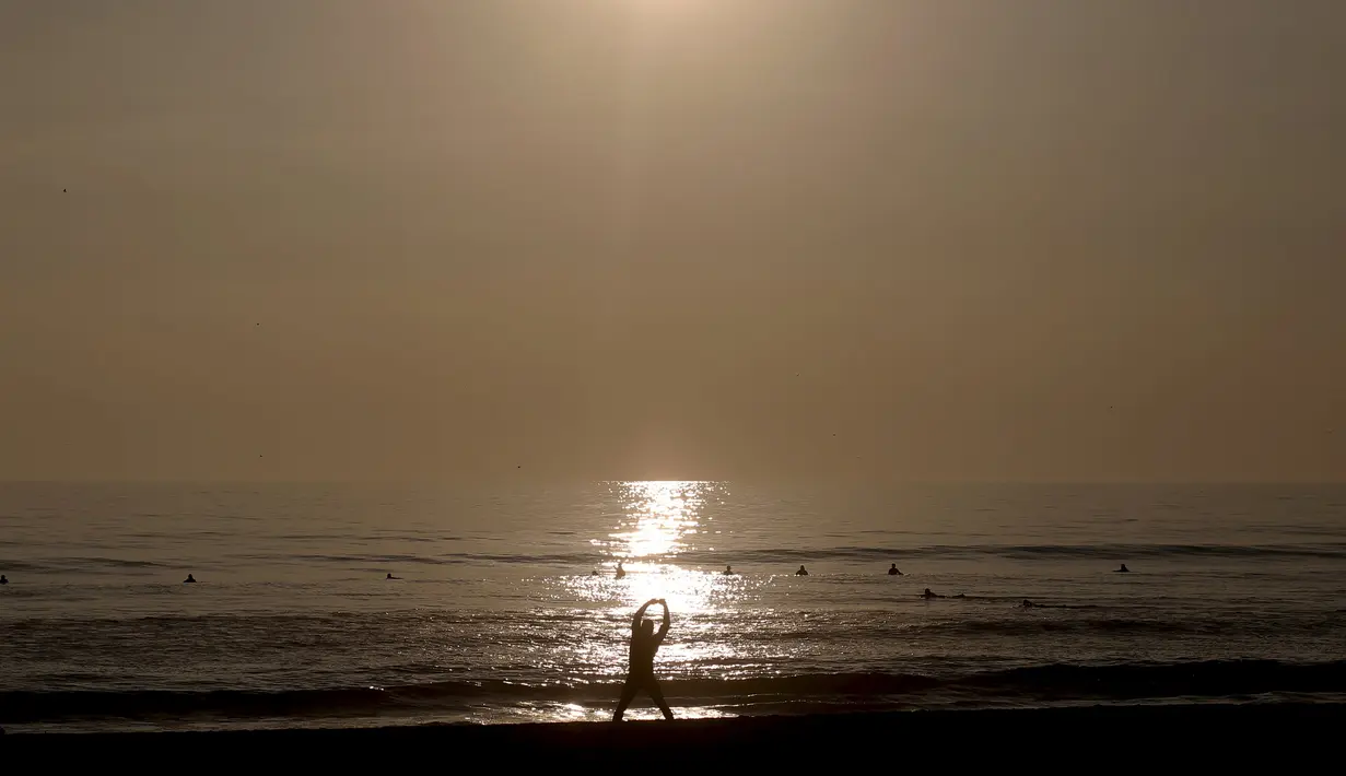Seorang pria melakukan pemanasan sebelum berselancar di sebuah pantai di La Serena, Chile, Selasa (23/5/2015). (REUTERS/Marcos Brindicci)