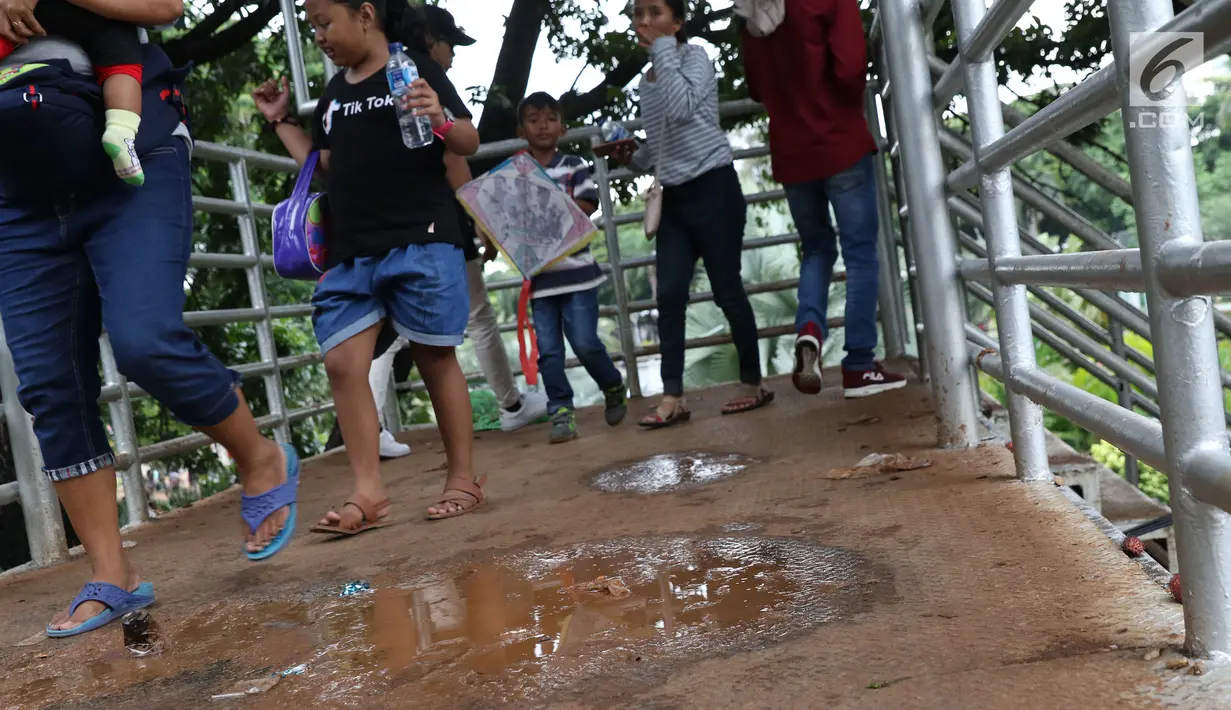 Sisa genangan air terlihat di koridor Jembatan Penyebrangan Orang (JPO) Jalan Medan Merdeka Barat, Jakarta, Selasa (1/1). Hal ini mengganggu kenyamanan warga yang melintas di JPO Medan Merdeka Barat. (Liputan6.com/Helmi Fithriansyah)