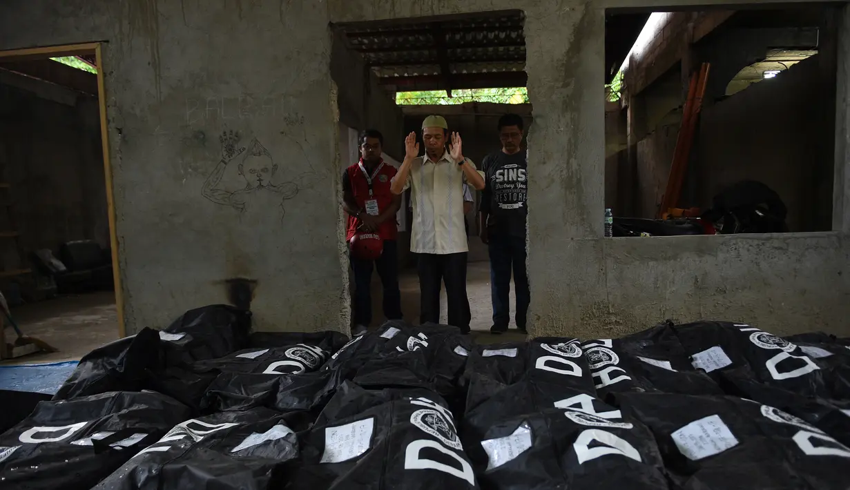 Seorang imam berdoa di depan jenazah korban pengepungan Marawi sebelum dimakamkan di sebuah pemakaman di Iligan City, di pulau selatan Mindanao (24/7). Pemerintah Filipina memperpanjang darurat militer di Marawi hingga akhir tahun. (AFP Photo/Ted Aljibe)