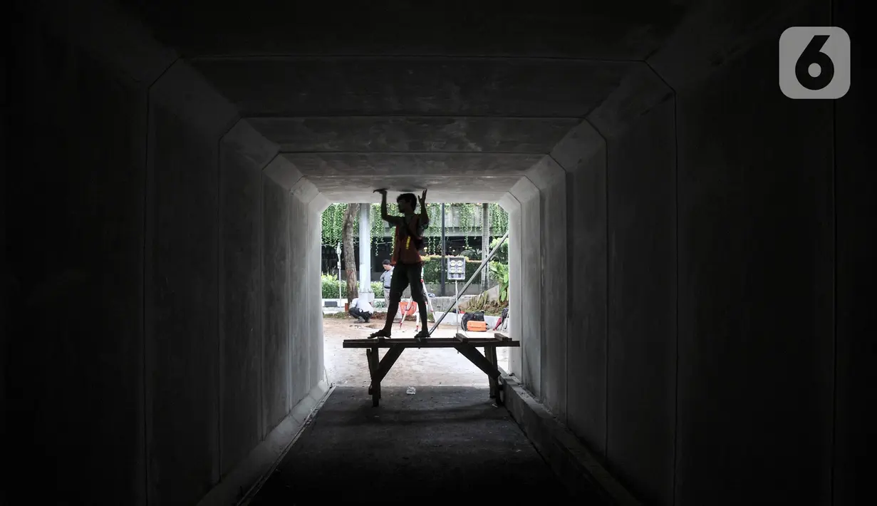 Aktivitas pekerja saat menyelesaikan pembangunan proyek jalur sepeda di Terowongan Semanggi, Jakarta, Kamis (6/10/2022). Diketahui, Pemerintah Provinsi DKI Jakarta berencana membangun jalur sepeda sepanjang 196,45 kilometer pada 26 ruas jalan di wilayah Ibu Kota, terdiri atas 40,06 kilometer jalur sepeda terproteksi, 154,73 kilometer jalur sepeda berbagi, dan 1,67 jalur sepeda di trotoar. (merdeka.com/Iqbal S. Nugroho)