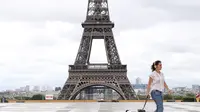 Seorang perempuan membawa anjingnya berjalan-jalan di Istana Trocadero tak jauh dari Menara Eiffel di Paris, 10 Juli 2020. Jumlah kematian terkait corona di Prancis naik menjadi 30.004, sementara jumlah pasien yang dirawat di rumah sakit atau di ICU terus turun pada Jumat (10/7). (Xinhua/Gao Jing)