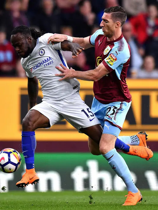 Pemain Chelsea, Victor Moses berebut bola dengan pemain Burnley, Stephen Ward dalam lanjutan Premier League di Turf Moor, Jumat (20/4). Gol bunuh diri Kevin Long dan tembakan Victor Moses memenangkan Chelsea dengan skor 2-1. (Anthony Devlin/PA via AP)