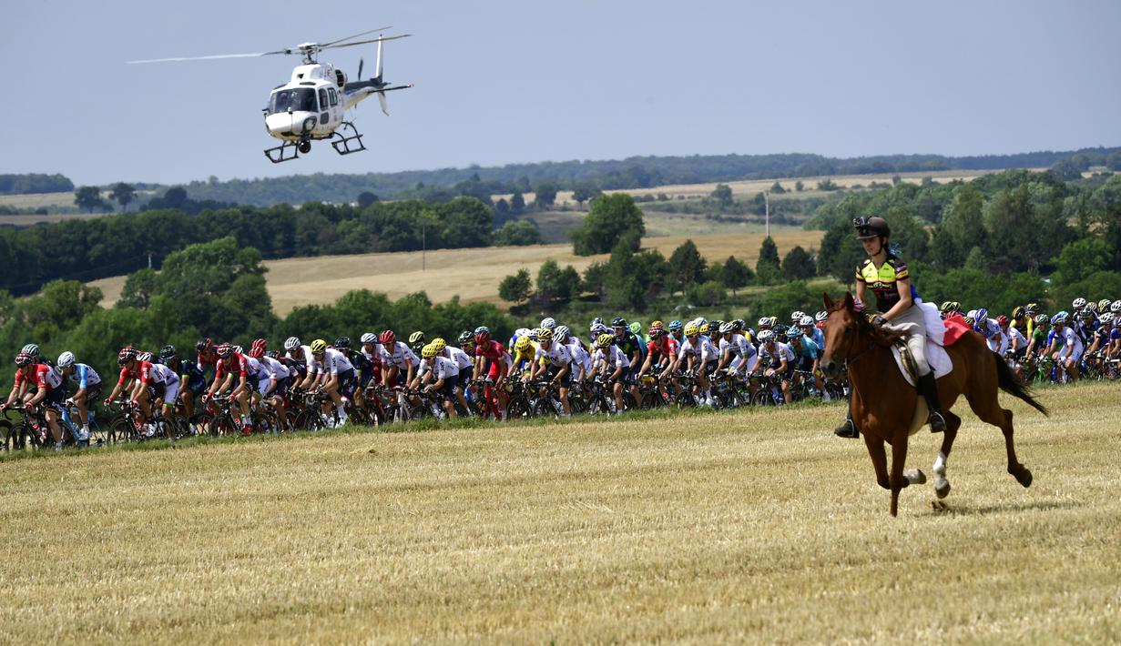 Seorang wanita menunggang kuda mengikuti pebalap  pada etape ketujuh Tour de France yang memiliki jarak tem[puh 213,5 km antara Troyes dan Nuits-Saint-Georges, (7/7/2017). (AFP/Philippe Lopez)