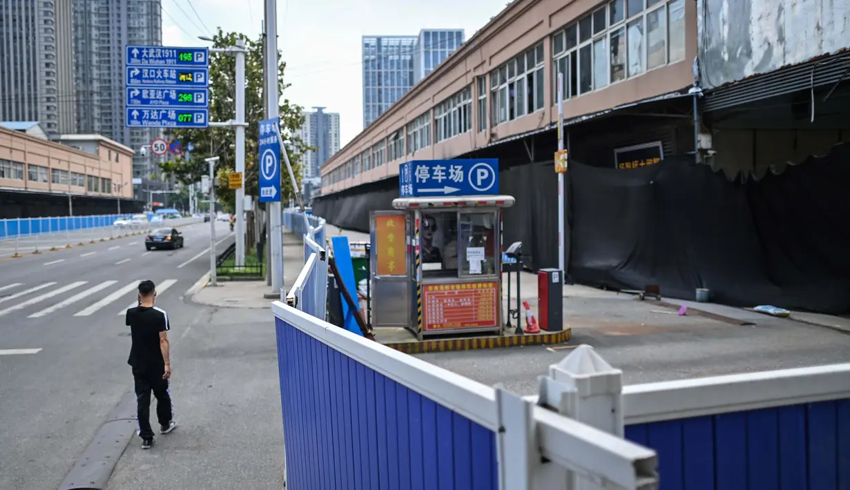 Seorang pria berjalan di samping Pasar Grosir Makanan Laut Huanan yang masih tutup di Wuhan, Provinsi Hubei, China, 4 Agustus 2020. Wuhan kembali pulih sejak karantina terkait COVID-19 dicabut. (Hector Retamal/AFP)