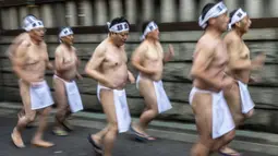 Penganut Shinto berlari saat melakukan pemanasan sebelum mandi dengan air dingin di Kuil Teppozu Inari, Tokyo, Jepang, 8 Januari 2023. Ritual Tahun Baru ini dilakukan untuk memurnikan jiwa dan raga. (Philip FONG/AFP)