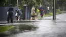 Orang-orang berjalan melewati banjir di Hastings, tenggara Auckland, Selandia Baru, Selasa (14/2/2023). Badai itu sampai mengakibatkan listrik di puluhan ribu rumah padam. Layanan kereta di Auckland juga dibatalkan. Perpustakaan hingga sekolah juga ditutup selama badai melanda negara itu. (Paul Taylor/Hawkes Bay Today via AP)