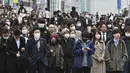 Komuter menunggu lampu lalu lintas di persimpangan di distrik Shinjuku Tokyo pada hari pertama pemerintah Jepang mencabut ketentuan wajib mengenakan masker, Senin (13/3/2023). Meski begitu, pemerintah Jepang masih merekomendasikan penggunaan masker di dalam ruangan dan tidak diwajibkan untuk di luar ruangan. (Photo by Kazuhiro NOGI / AFP)