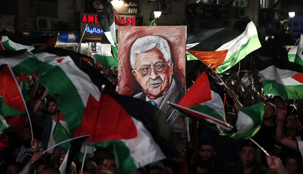 Warga Palestina membawa bendera nasional dan foto Presiden Mahmud Abbas saat menunggu live-screening pidato Presiden mereka sebelum pengibaran bendera Palestina di markas besar PPB di New York, Rabu (30/9/2015). (AFP PHOTO/ABBAS Momani)