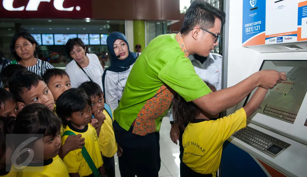 Petugas KAI menunjukan cara memesan tiket kepada murid PAUD di Stasiun Gambir, Jakarta, Senin (20/3). PT KAI mengajak anak Indonesia untuk mengenal lebih jauh tentang kereta api sekaligus memperingati hari dongeng sedunia. (Liputan6.com/Gempur M Surya)