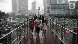 Warga berjalan di JPO Bundaran HI, Jakarta, Rabu (28/12/2022). Walau sempat disebutkan ada potensi badai dahsyat yang melanda kawasan Jakarta–Bogor–Depok–Tangerang–Bekasi (Jabodetabek) pada hari ini, warga Jakarta terpantau masih banyak beraktivitas di luar ruangan. (Liputan6.com/Faizal Fanani)