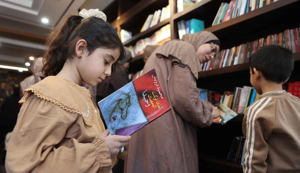Seorang gadis pengungsi Palestina membaca buku di perpustakaan Al-Ankaa (Phoenix), perpustakaan pertama yang dibuka sejak gencatan senjata di Jalur Gaza yang berisi buku-buku yang diselamatkan dari perpustakaan yang hancur selama perang Israel-Hamas, di lingkungan Rimal, Kota Gaza pada Selasa 21 April 2026. Di tengah kesepakatan gencatan senjata antara Israel dan Hamas, beberapa pengungsi Palestisna menyempatkan meluangkan waktu mendatangi dan membaca buku-buku di perpustakaan Al-Ankaa atau Phoenix Library. (Omar AL-QATTAA/AFP)