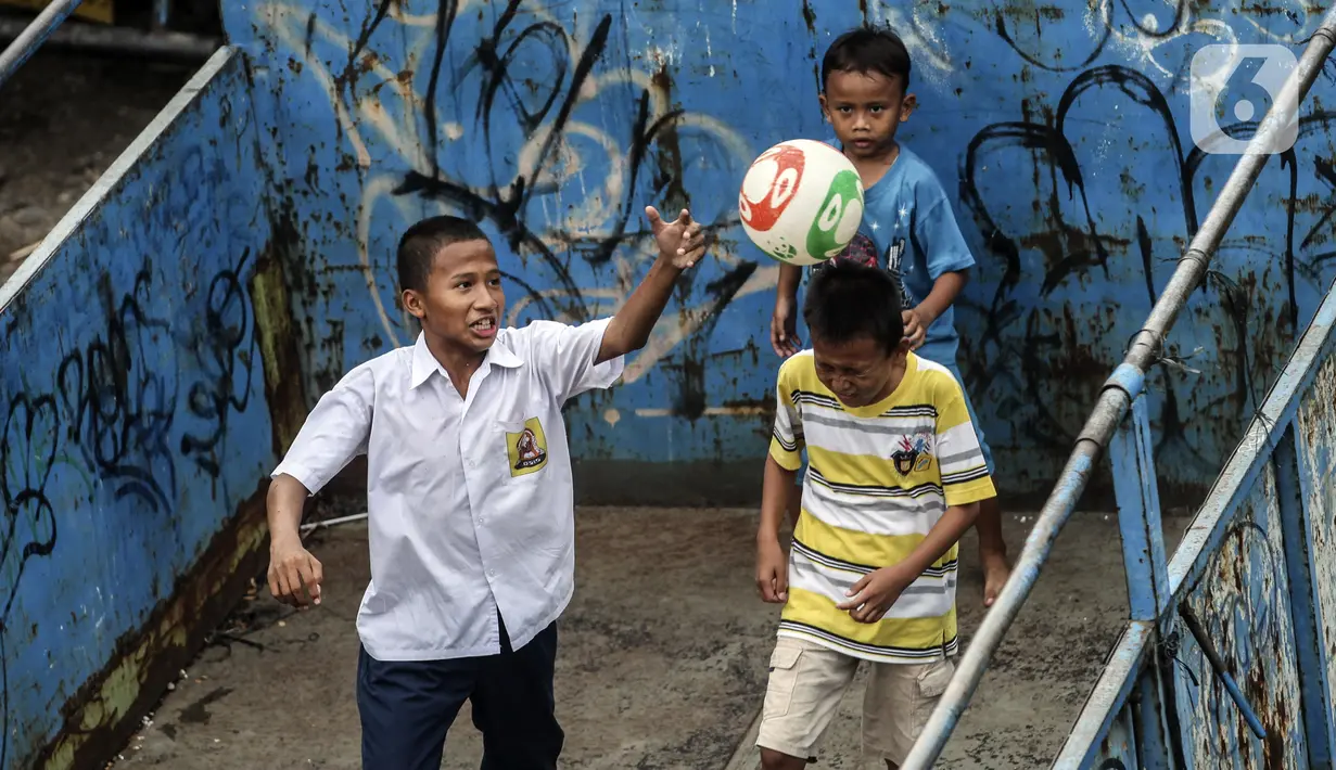 Sejumlah anak bermain sepak bola dalam bak truk di kawasan Cengkareng, Jakarta, Rabu (23/2/2022). Minimnya lahan bermain di kawasan tersebut membuat anak-anak memanfaatkan tempat yang bukan semestinya untuk bermain bola. (Liputan6.com/Johan Tallo)