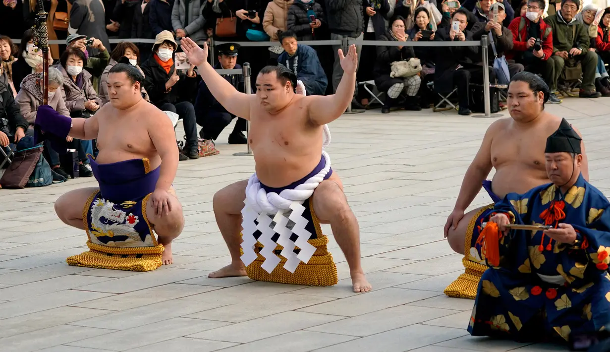 Juara Grand Sumo asal Mongolia, Kakuryu (kedua kiri) melakukan upacara mengentakkan kaki di Kuil Shinto Meiji Shrine, Tokyo, Selasa (9/1). Merujuk kepada Wikipedia, ritual tersebut dikenal dengan nama shiko. (AP/Shizuo Kambayashi)