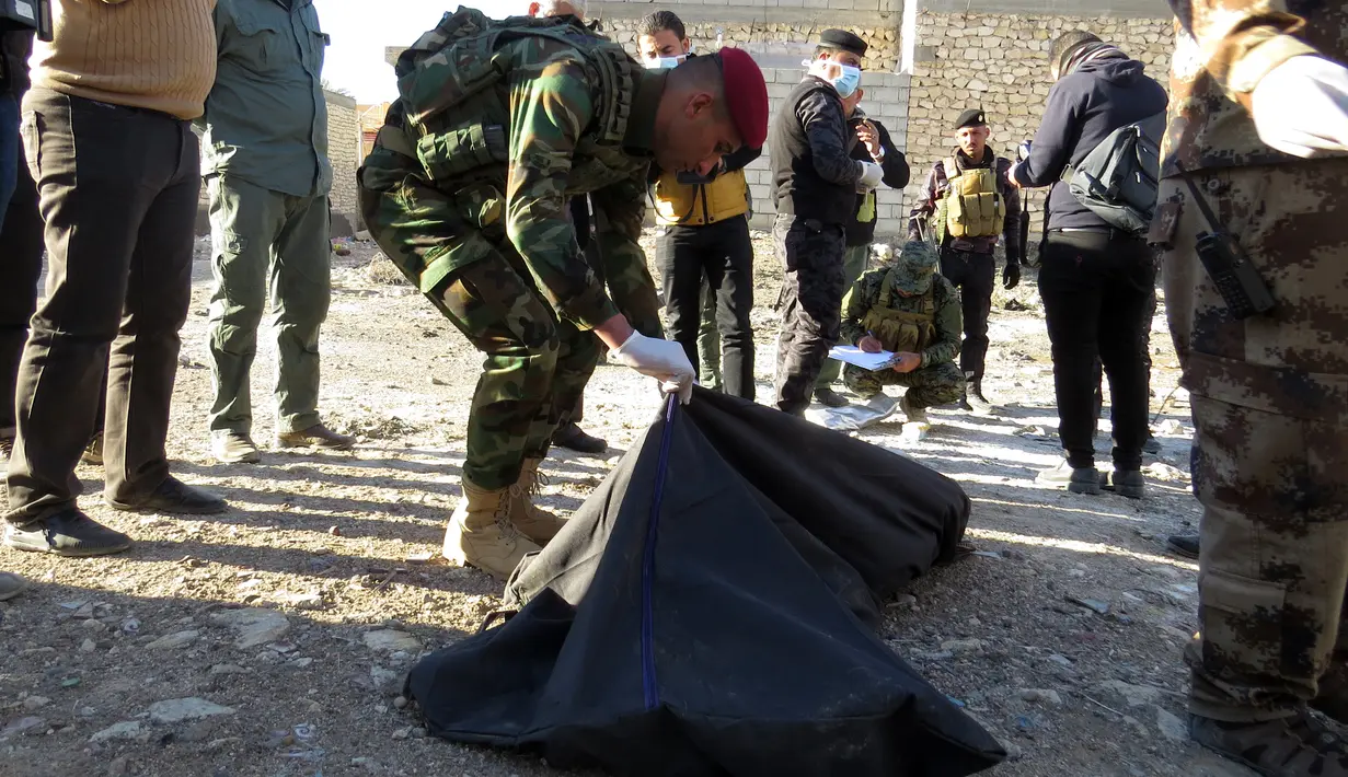 Polisi Irak memasukkan jasad korban kesadisan kelompok ISIS ke kantong jenazah, di sebuah kuburan massal yang ditemukan di Kota Ramadi, sebelah barat Baghdad, Selasa (26/1). Kuburan massal tersebut berisi sisa-sisa sekitar 40 jasad (AFP/ MOADH AL-DULAIMI)