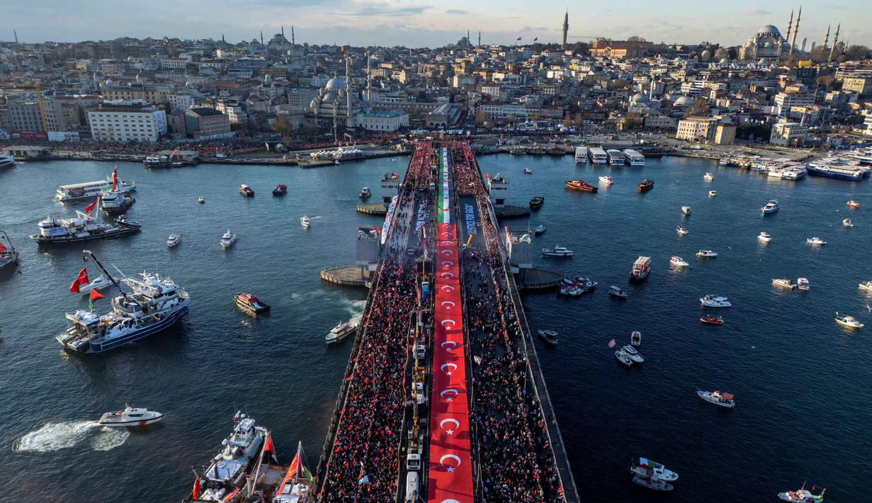 Mereka menyerukan segera diakhirinya genosida di Gaza. Tampak foto udara menunjukkan ribuan orang yang berdemonstrasi menunjukkan solidaritas mereka dengan rakyat Palestina di tengah perang yang sedang berlangsung antara Israel dan kelompok Hamas di wilayah Gaza, di Jembatan Galata, Istanbul, Turki pada 1 Januari 2026. (Yasin AKGUL/AFP)