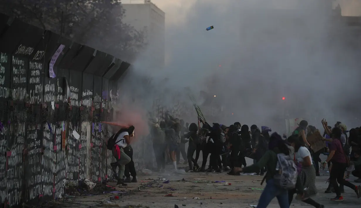 Demonstran menyerang barikade yang melindungi Istana Nasional selama pawai memperingati Hari Perempuan Internasional dan memprotes kekerasan gender di Mexico City, Meksiko, Senin (8/3/2021). Hari Perempuan Internasional diperingati setiap tanggal 8 Maret. (AP Photo/Rebecca Blackwell)
