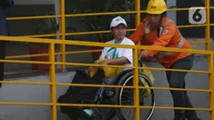 Pekerja PT Kereta Api Indonesia (Persero) membantu salah satu penyandang disabilitas yang mengikuti program Mudik Gratis di Stasiun Pasar Senen, Jakarta, Minggu (7/4/2024). (Liputan6.com/Helmi Fithriansyah)