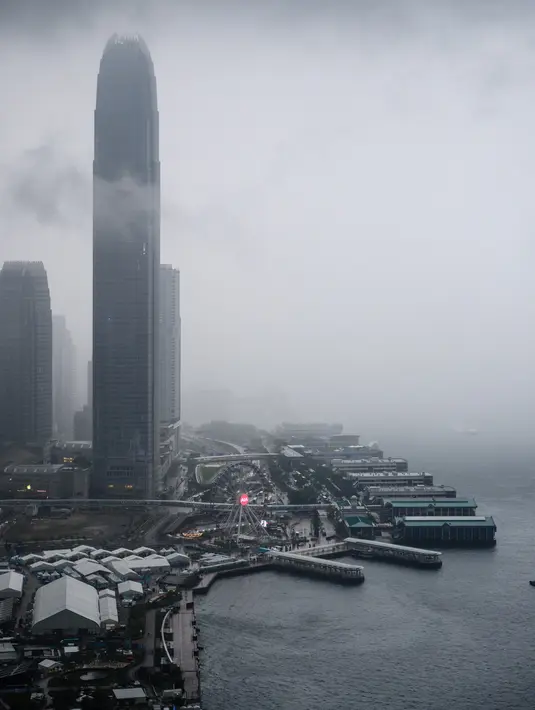 Pemandangan gedung IFC (International Finance Center) menjulang di atas dermaga Central saat badai awan terjadi sebelum hujan lebat di atas Pelabuhan Victoria Hong Kong (6/3). (AFP Photo/Anthony Wallace)