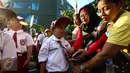 Orangtua merapikan seragam anaknya sebelum upacara pada hari pertama sekolah di SDN Pasar Baru 05 Jakarta, Senin (18/7). Usai libur Idul Fitri, para siswa kembali mengikuti pelajaran di sekolah untuk tahun ajaran 2015-2016. (Liputan6.com/Faizal Fanani)