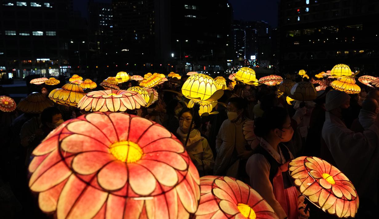 Umat Buddha Korea Selatan mengenakan masker membawa lentera lotus berwarna-warni selama upacara pencahayaan untuk merayakan ulang tahun Buddha yang akan datang pada 8 Mei, di Seoul, Korea Selatan (5/4/2022). (AP Photo/Lee Jin-man)