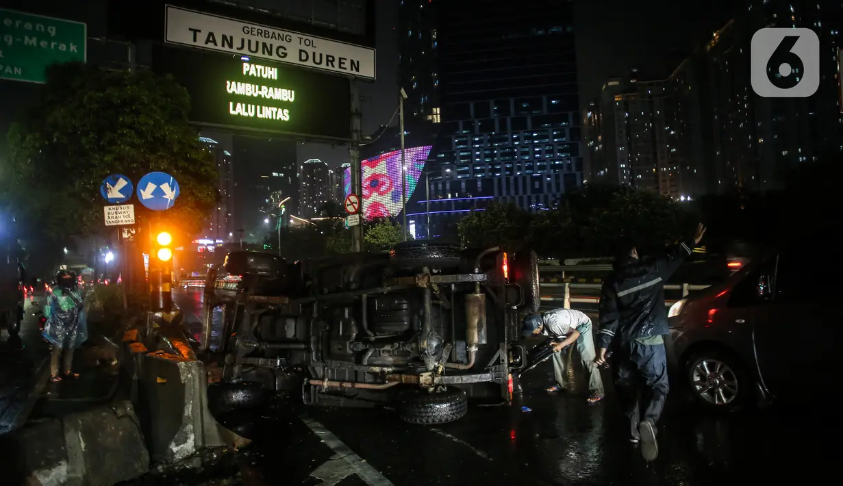 Petugas berusaha memindahkan mobil jenis jeep yang terguling di depan gerbang Tol Tanjung Duren, Jalan S Parman, Jakarta Barat, Minggu (26/9/2021). Tidak ada korban jiwa, namun kecelakaan tersebut membuat lalu lintas di jalan itu terimbas kemacetan yang cukup panjang. (Liputan6.com/Johan Tallo)