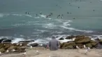 Seorang pria menyaksikan Pantai Maroubra yang dibuka kembali di Sydney (20/4/2020). Pihak berwenang di Sydney membuka kembali tiga pantai untuk aktivitas warga yang ingin berenang ataupun berselancar di tengah pembatasan sosial yang diberlakukan di tengah wabah Covid-19. (AFP/Saeed Khan)