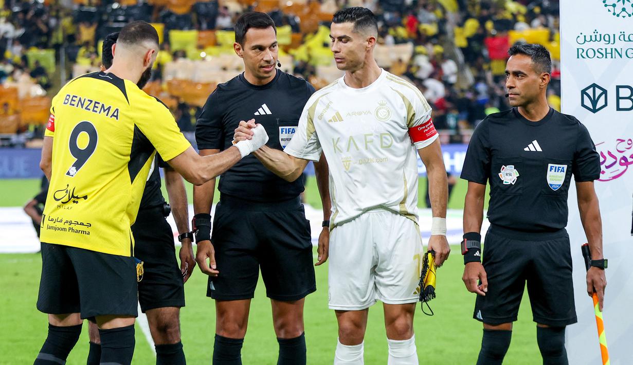 Pemain Al Nassr, Cristiano Ronaldo (kanan) bersalaman dengan pemain Ittihad FC, Karim Benzema sebelum sepak mula pada laga lanjutan Liga Arab Saudi di King Abdullah Sports City, Jeddah, Arab Saudi, Sabtu (07/12/2024) dini hari WIB. (AFP)