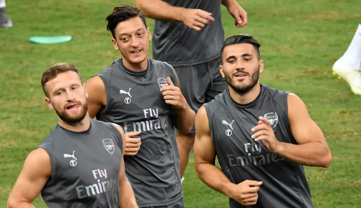 Gelandang Arsenal Mesut Ozil (tengah) bersama rekan-rekannya melakukan pemanasan saat mengikuti sesi latihan tim di Singapura (27/7). Arsenal akan bertanding melawan PSG pada International Champions Cup 28 Juli. (AFP Photo/Roslan Rahman)