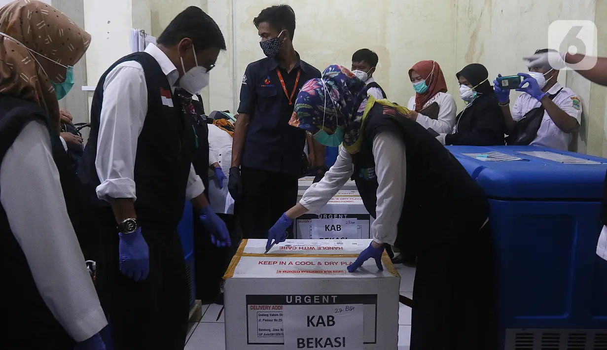 Kepala Dinkes Kabupaten Bekasi, dr Sri Enny Mainarti membuka kotak berisi vaksin Covid-19 Sinovac setibanya di Gudang UPTD Farmasi Kabupaten Bekasi,  Tambun, Rabu (27/1/2021). Sebanyak 12.000 dosis vaksin COVID-19 dari Biofarma Bandung tiba di Kabupaten Bekasi. (Liputan6.com/Herman Zakharia)
