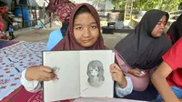 Yaya sedang menunjukan hasil lukisannya di Sanggar Disabilitas Prestasi Rindani Kota Jambi, Jumat (19/7/2024). Yaya merupakan disabilitas tunarungu yang berprestasi berkat bakatnya sebagai pelukis. (Liputan6.com/Gresi Plasmanto)