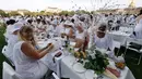 Orang-orang berpakaian putih berkumpul untuk makan malam bersama atau "Diner en Blanc" yang ke-30 di Paris, Prancis (3/6). “Diner en Blanc”, pertama kali dimulai oleh Mr. Francois Pasquier bersama teman dan kerabat di tahun 1988. (AFP/Francois Guillot)