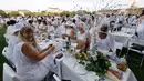 Orang-orang berpakaian putih berkumpul untuk makan malam bersama atau "Diner en Blanc" yang ke-30 di Paris, Prancis (3/6). “Diner en Blanc”, pertama kali dimulai oleh Mr. Francois Pasquier bersama teman dan kerabat di tahun 1988. (AFP/Francois Guillot)