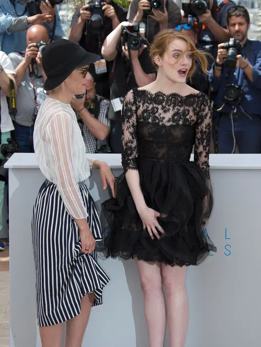 Aktris Emma Stone (kanan) ditemani Parker Posey berpose sambil memegangi roknya yang tersibak oleh angin, jelang pemutaran film Irrational Man, di Festival Film Cannes di Perancis, Jumat (15/5/2015). (REUTERS/Yves Herman)