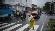 Seorang wanita tua yang mengenakan masker berjalan tanpa alas kaki melalui zebra cross di Kochi, negara bagian Kerala, India, Rabu (6/7/2022). Negara bagian selatan itu telah mewajibkan penggunaan masker di tempat-tempat umum menyusul meningkatnya kasus COVID-19. (AP Photo/ RS Iyer)